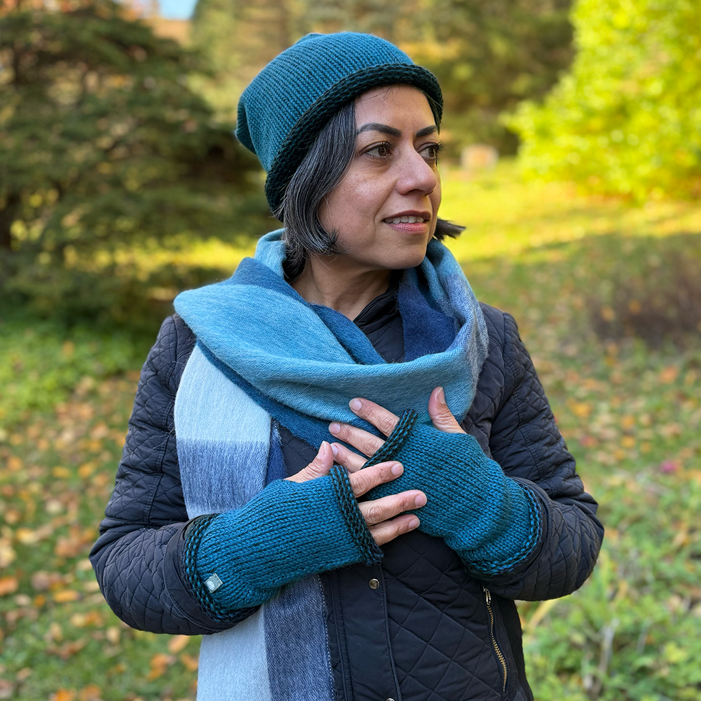 Knitted baby alpaca fingerless gloves on model teal with black trim with matching hat and alpaca scarf
