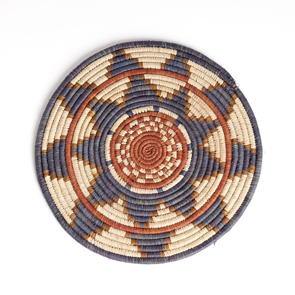 Round handwoven trivet with flower design in gray, orange and tan