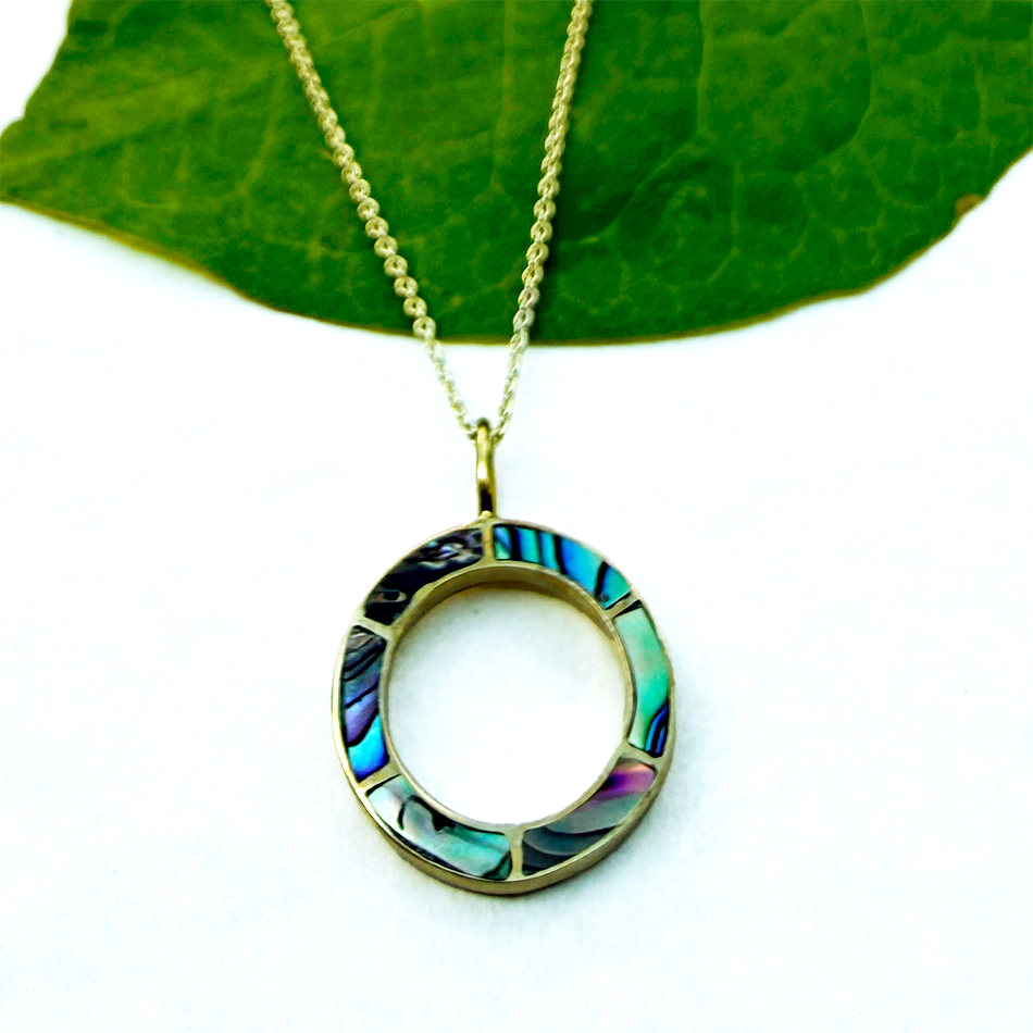 Brass circle pendant with inlaid abalone and gold chain.