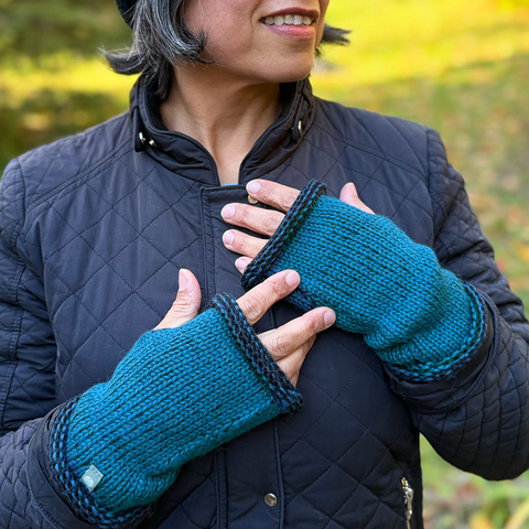 Knitted baby alpaca fingerless gloves on hands, teal with black trim
