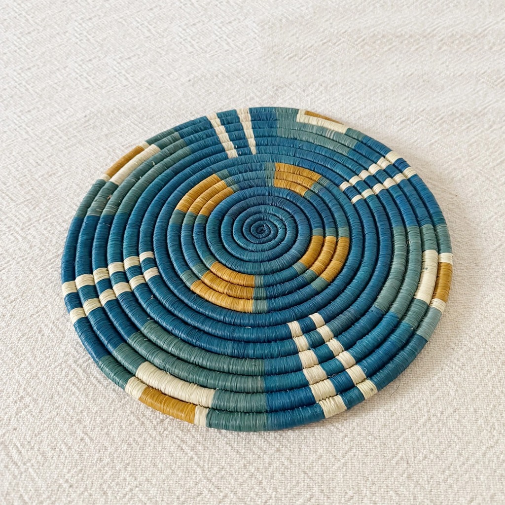 Round handwoven trivet with geometric design with blue green white and orange