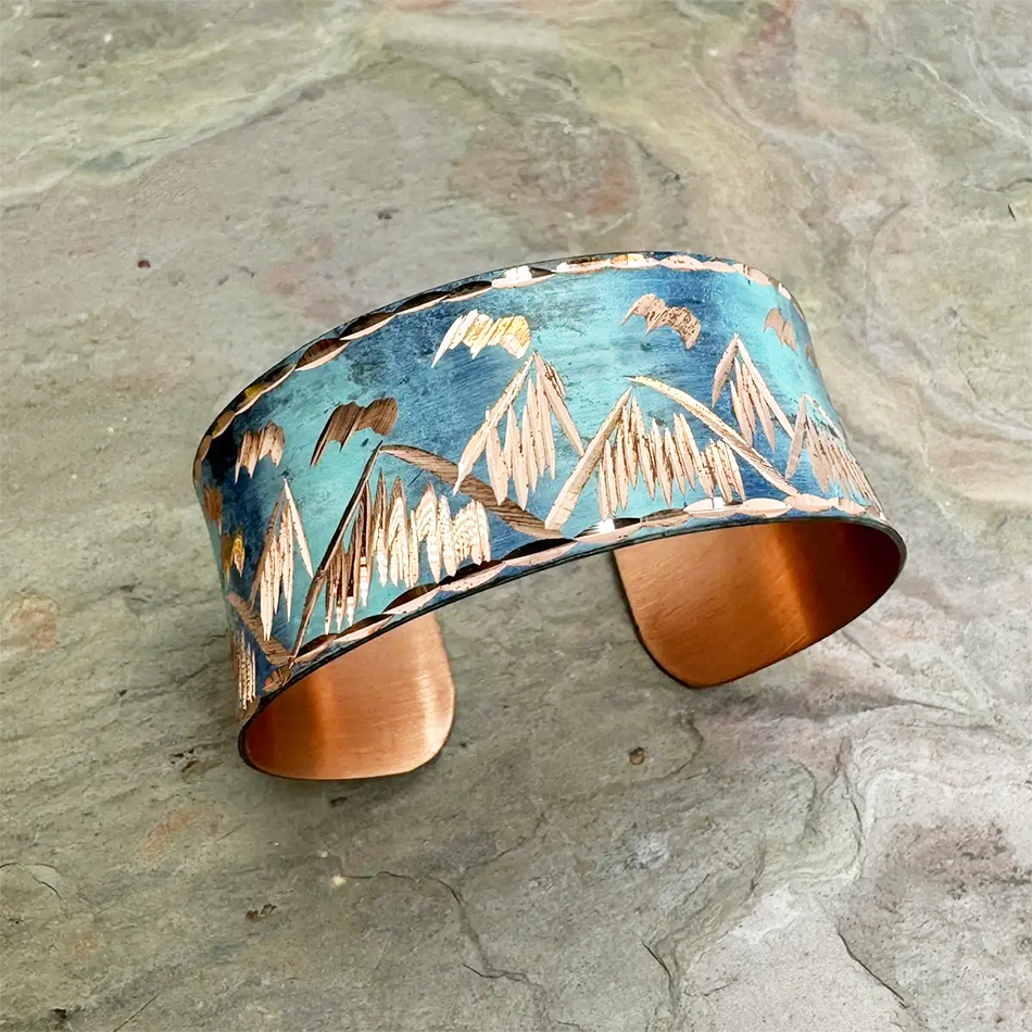 Copper cuff with blue patina and mountain design.