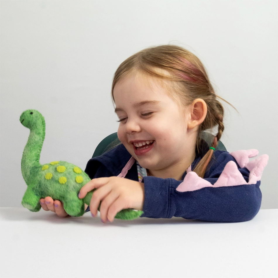 Child smiling and playin with green felt dinosaur
