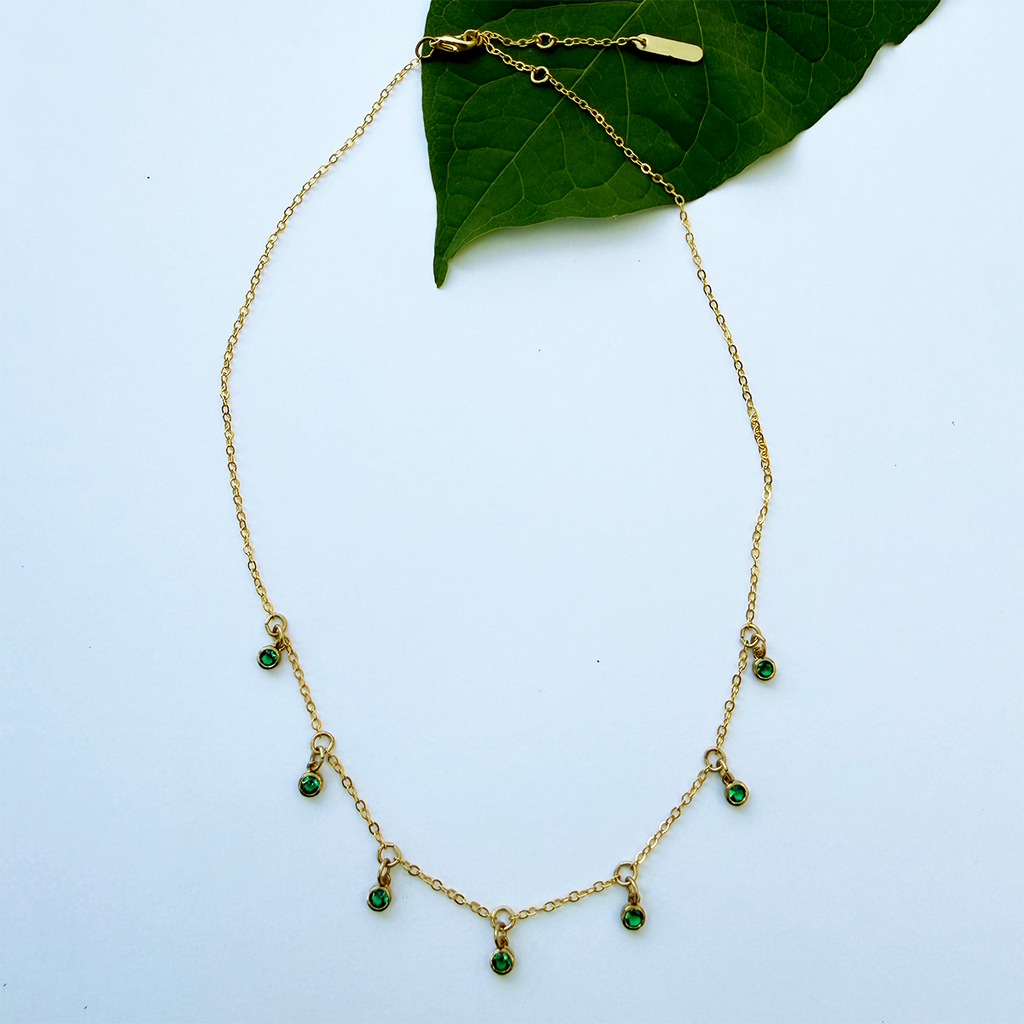 Necklace with delicate brass chain and 7 small green zircon stones hanging as charms.