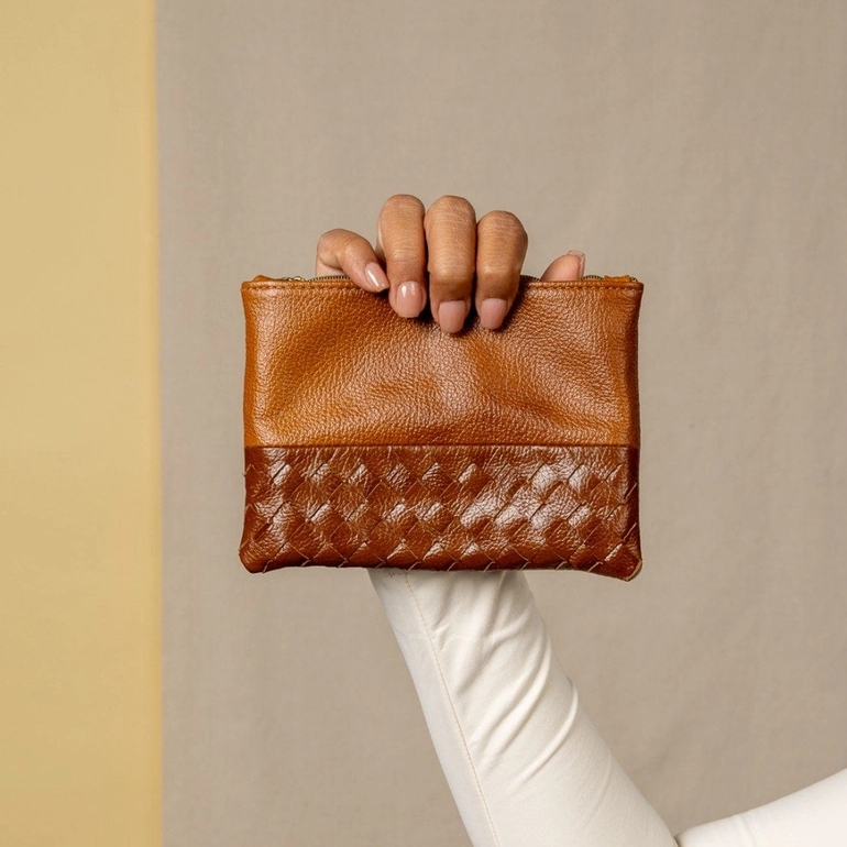 Light brown leather pouch with woven design on front with model holding it