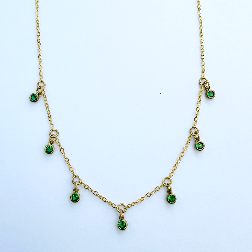 Necklace with delicate brass chain and 7 small green zircon stones hanging as charms.