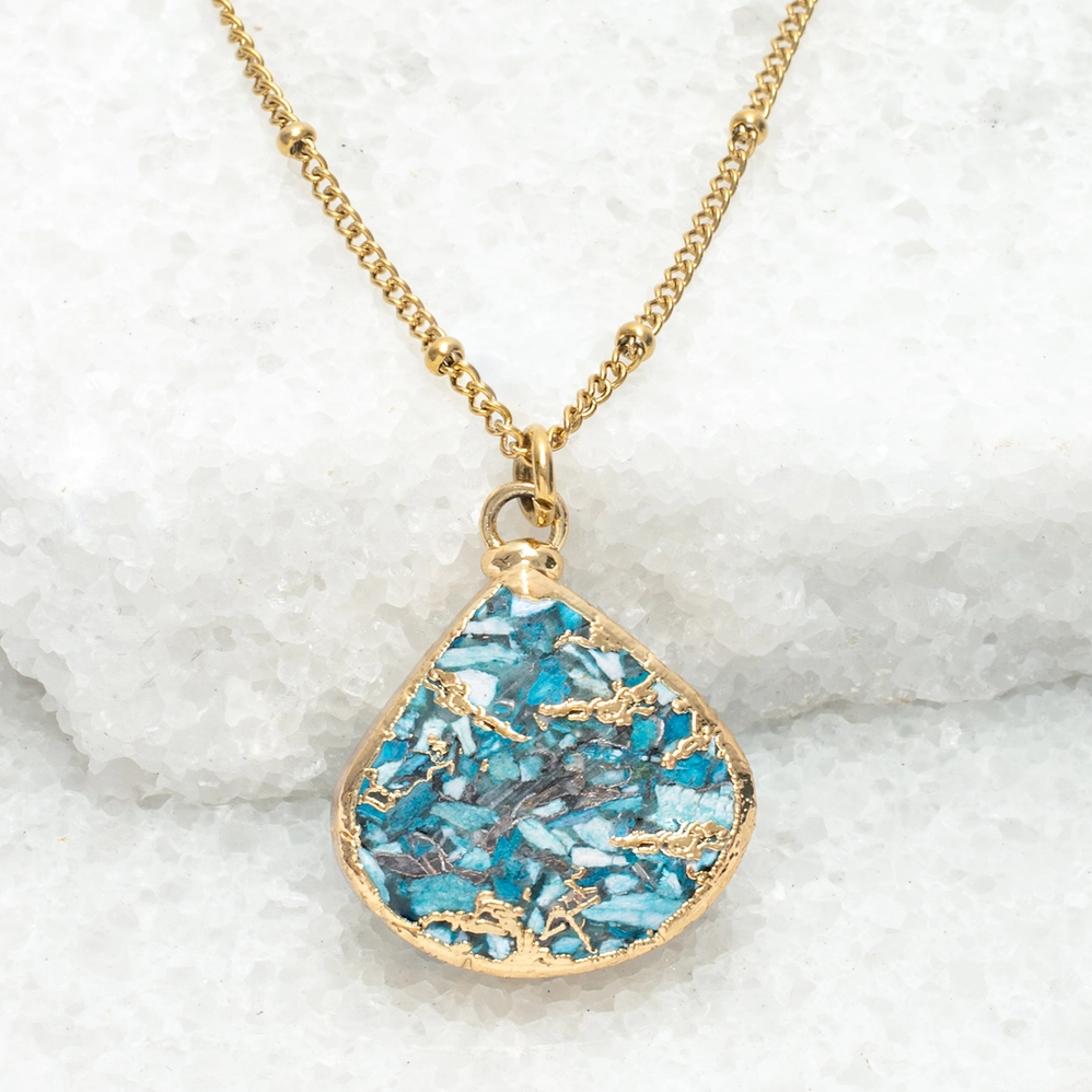 Close up of necklace with gold chain and fan-shaped turquoise and gold pendant