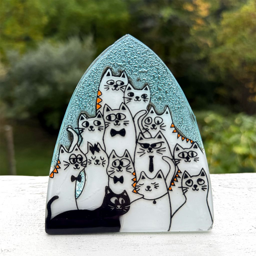 Glass nightlight with several white and one black cat