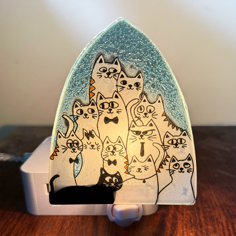Glass nightlight with several white and one black cat
