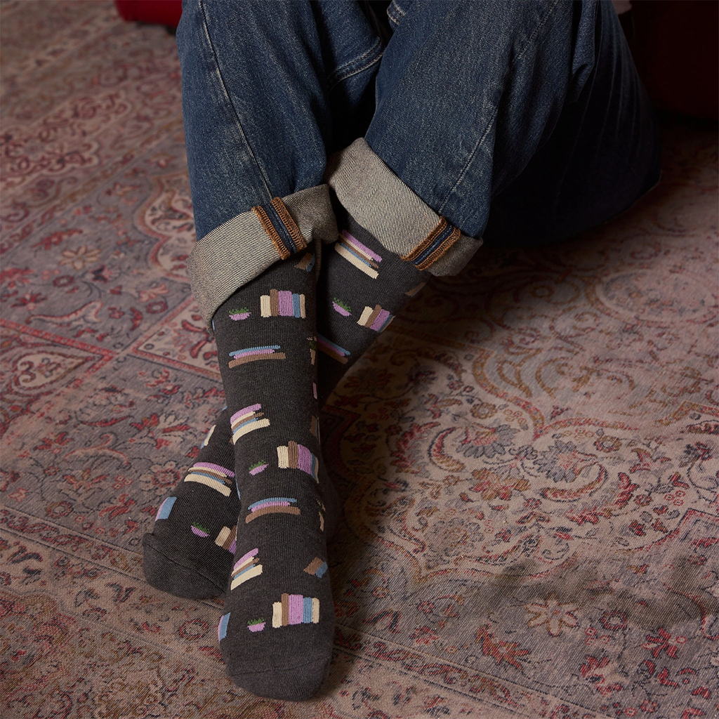 Charcoal colored socks with books on it as a design on person