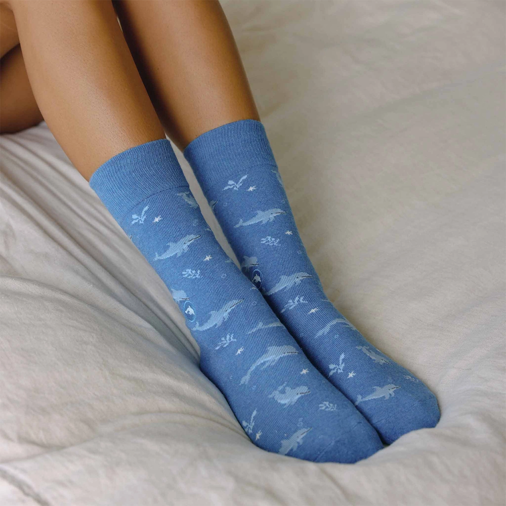Blue socks with white dolphins all over them on model's feet