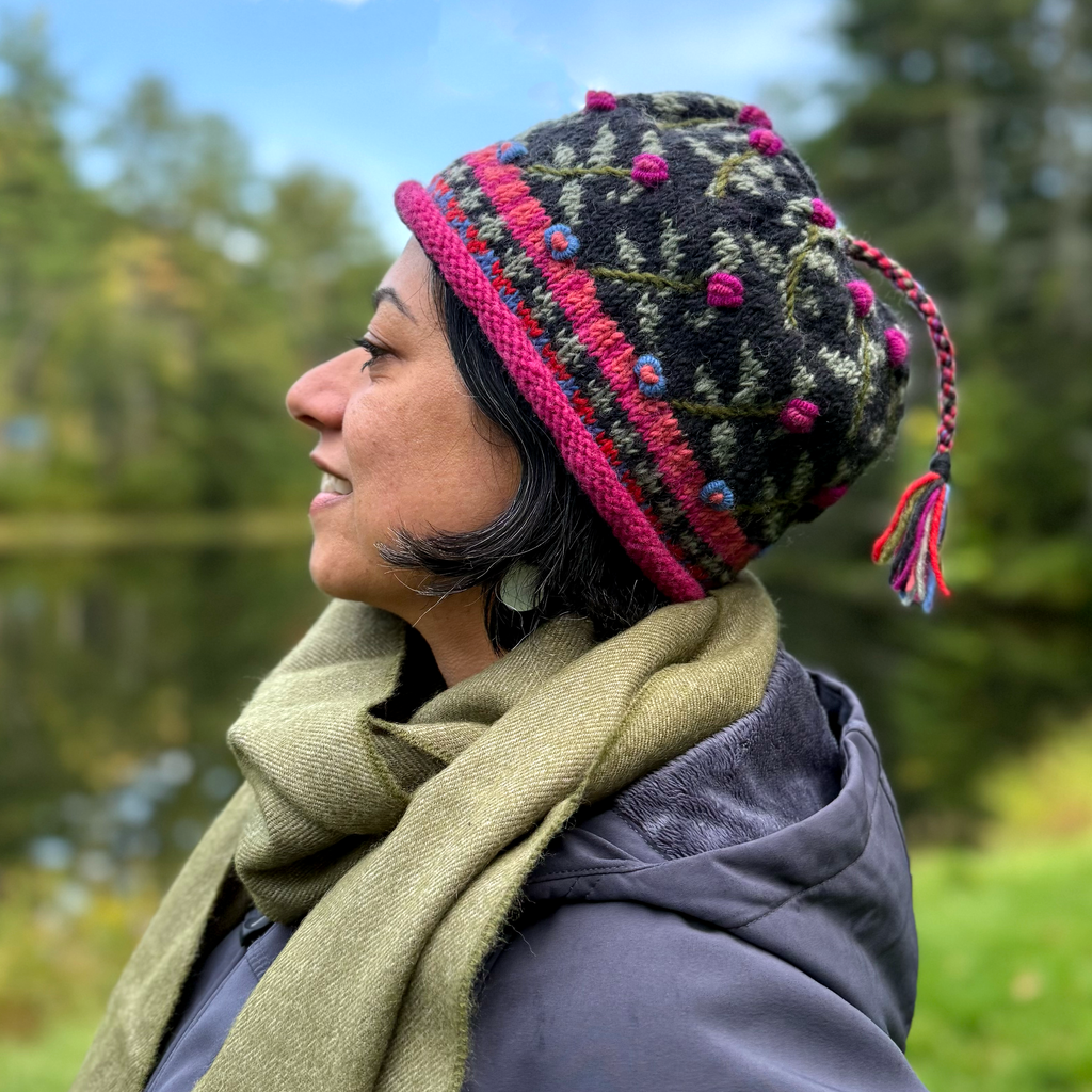 Wool knit hat on model black with bright green trim and tassel