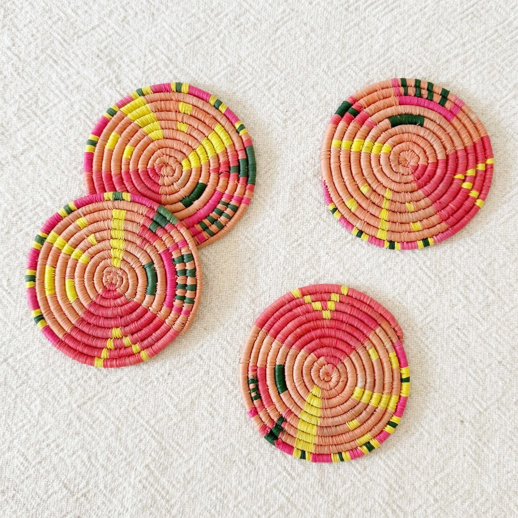 Set of 4 round handwoven coaster in pink, yellow and green geometric pattern.