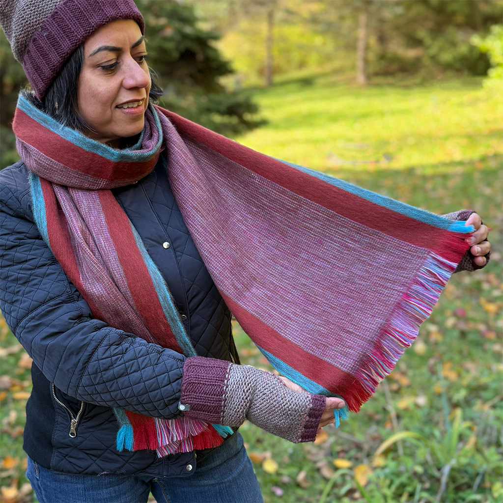 Model showing alpaca scarf with reds and turquoise colors stripes
