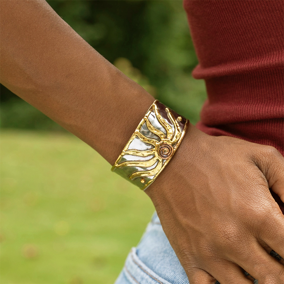 Silver-plated wide cuff with gold sun design.