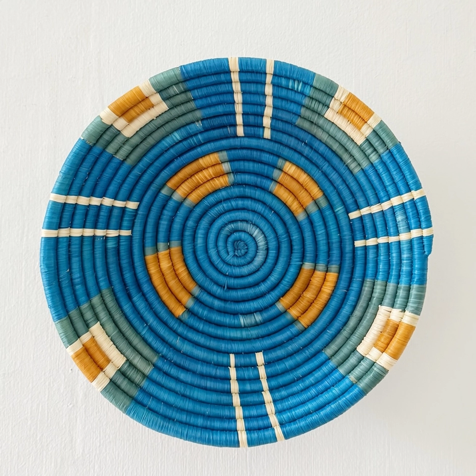 Round handwoven basket with blue background and orange squares and light green
