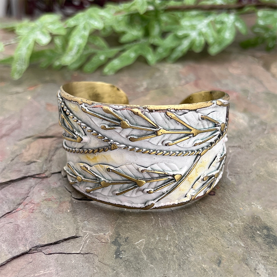 White and brass cuff with patina finish and brass leaf accents.
