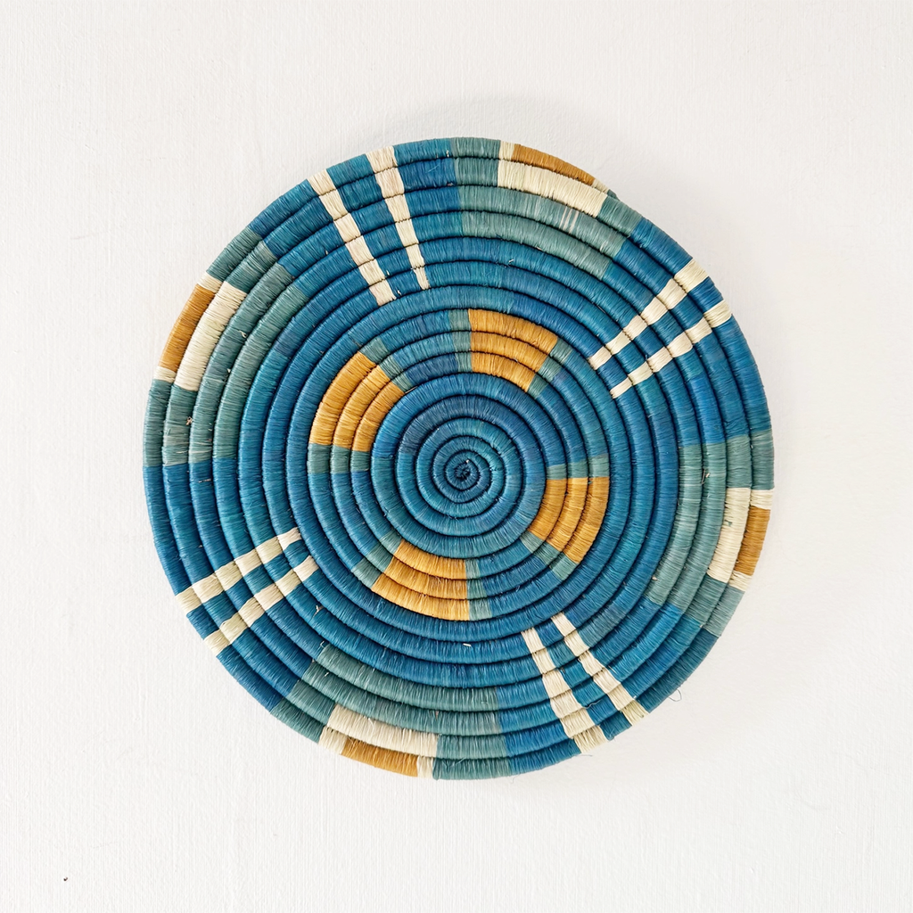 Round handwoven trivet with geometric design with blue green white and orange