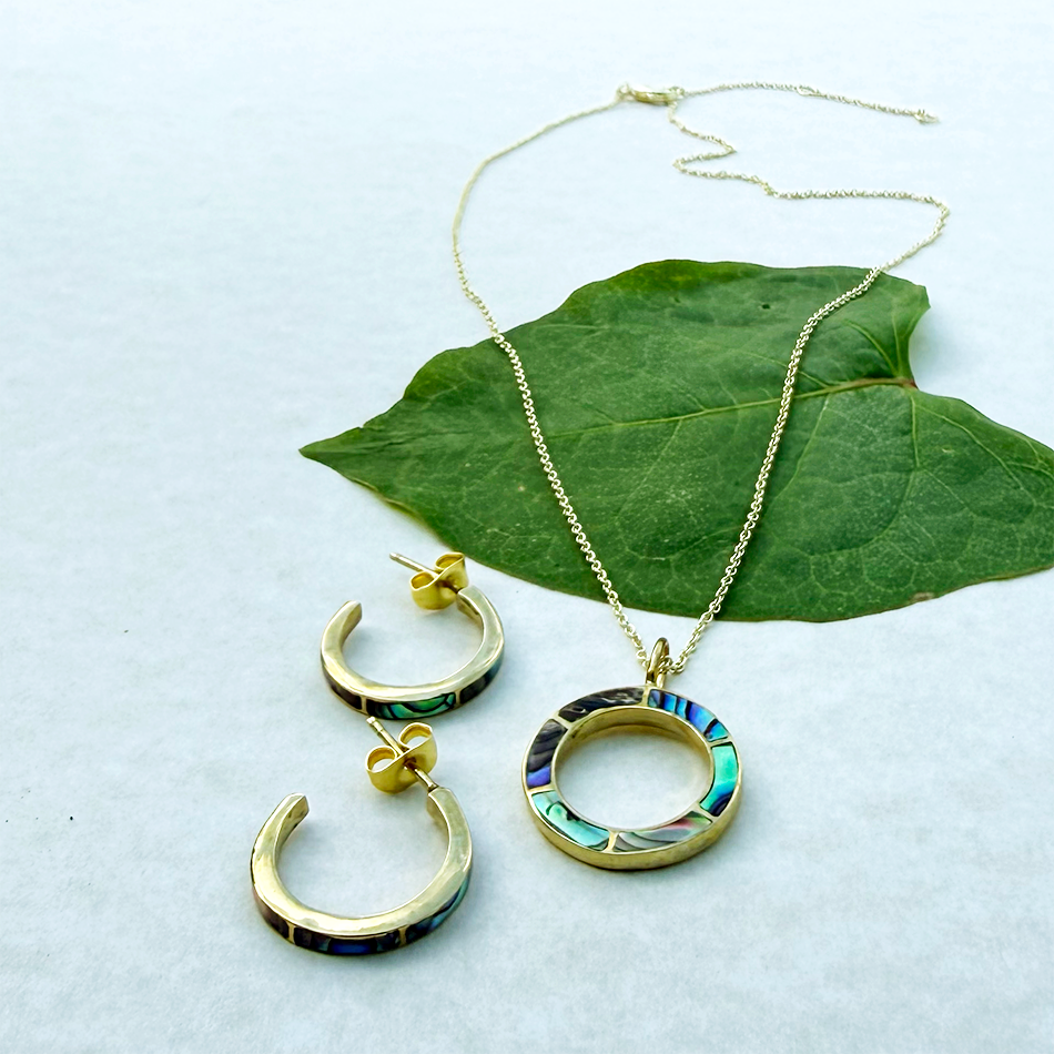 Brass circle pendant with inlaid abalone and gold chain and abalone brass huggies.