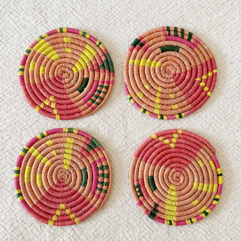 Set of 4 round handwoven coaster in pink, yellow and green geometric pattern.