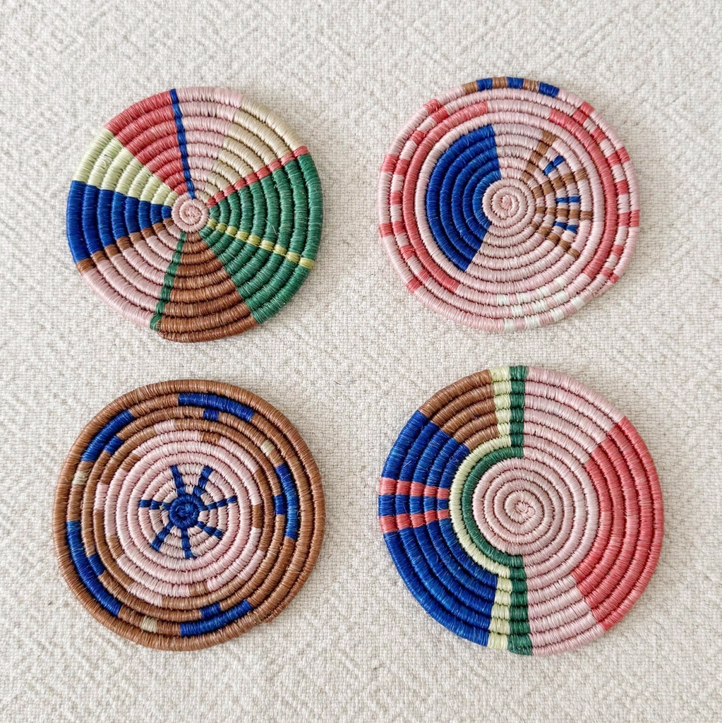 Set of 4 round handwoven coaster in pink, green, blue brown geometric pattern.