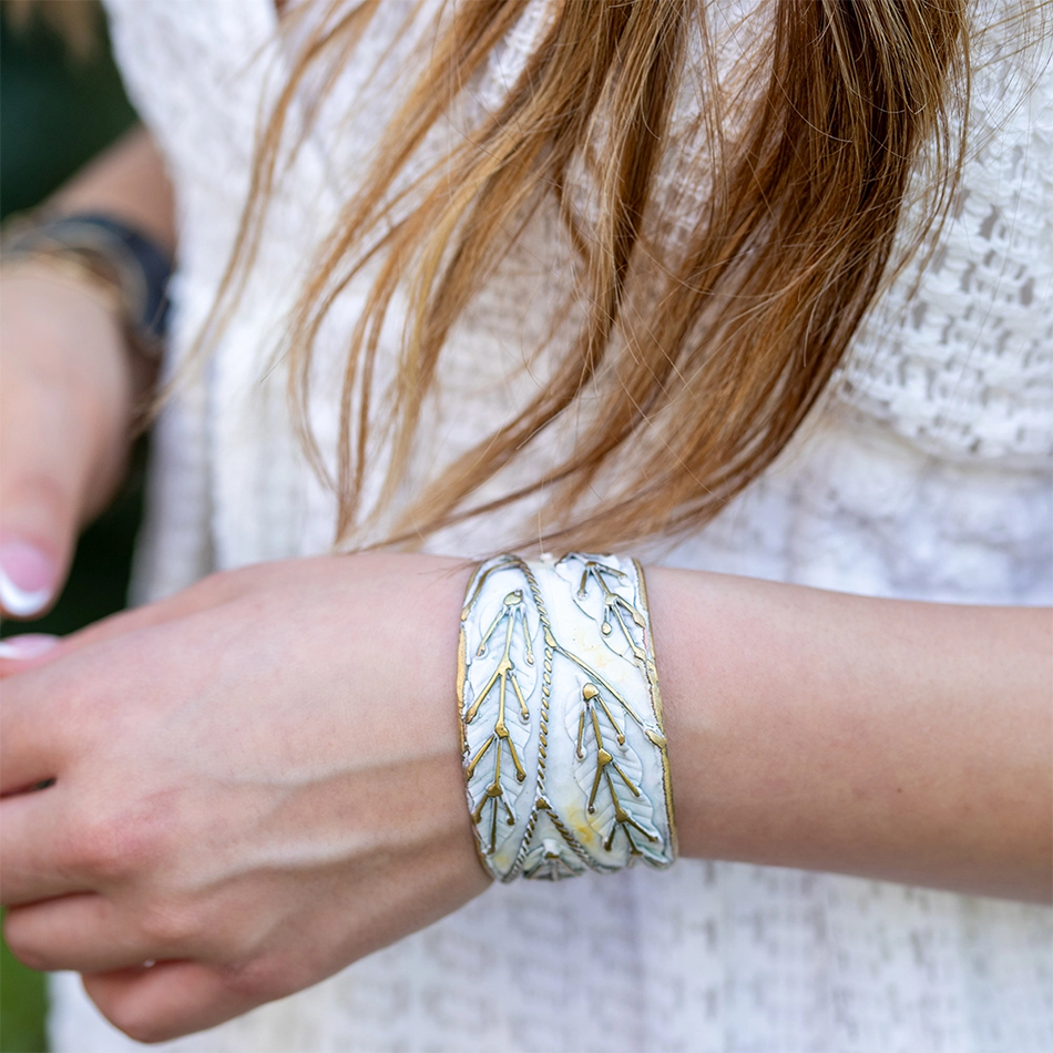 White and brass cuff with patina finish and brass leaf accents.