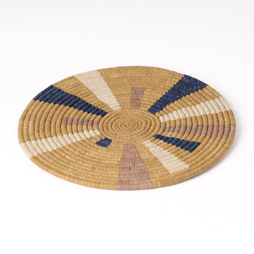Round trivet banana fiber tan with splashes of pink, white and blue