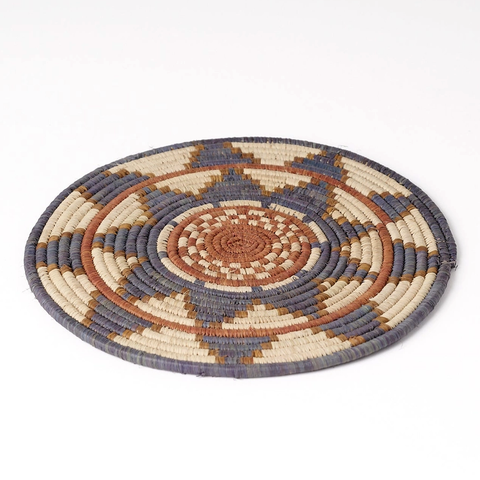 Round handwoven trivet with flower design in gray, orange and tan