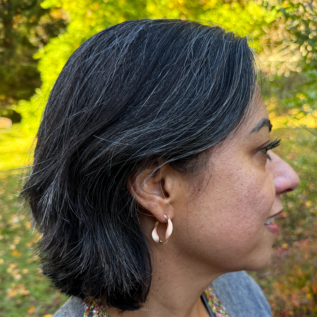 Gold huggie style earrings with a tangerine colored, shiny enamel