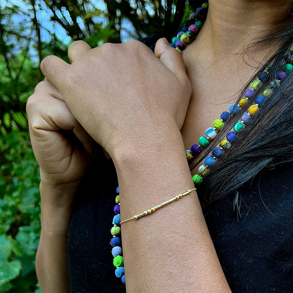 Gold morse code love bracelet handmade by survivors of human trafficking in Thailand on model
