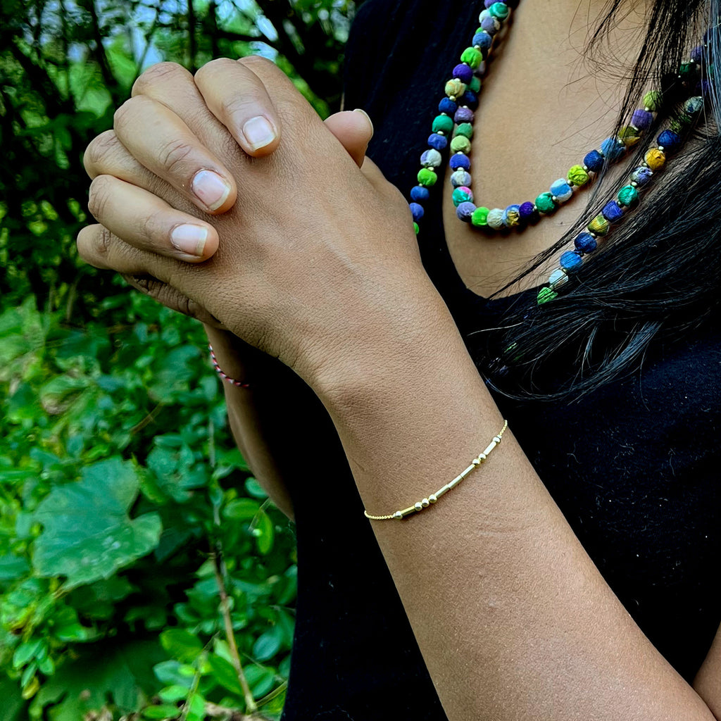 Gold morse code love bracelet handmade by survivors of human trafficking in Thailand on model
