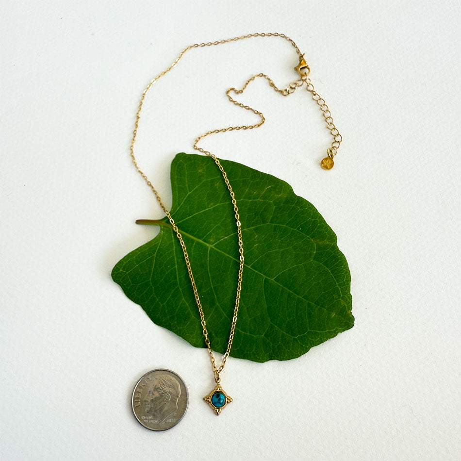 Gold-plated tiny compass necklace with turquoise stone in the center. 