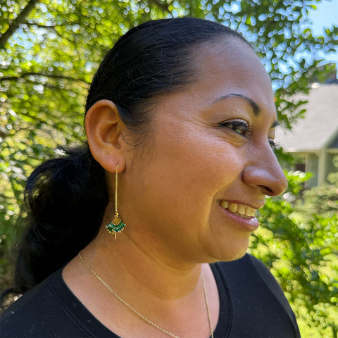 Fair trade earrings on gold chain with green beads.