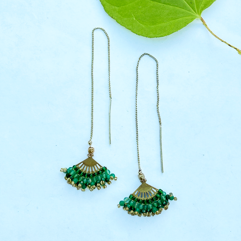 Fair trade earrings on gold chain with green beads.