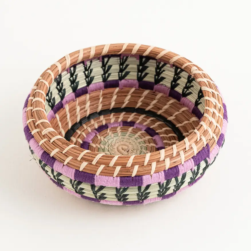 Fair trade small pine needle basket with purple and green accents.