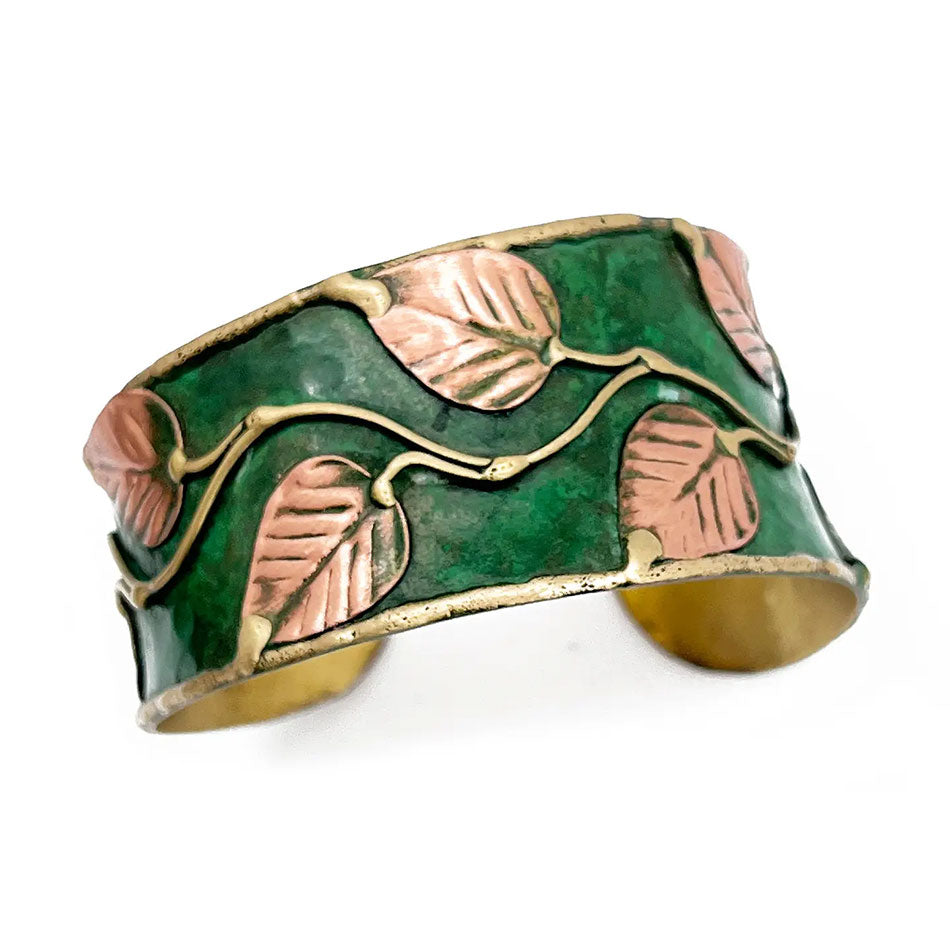 Fair trade cuff bracelet with green base and brass leaves on top.