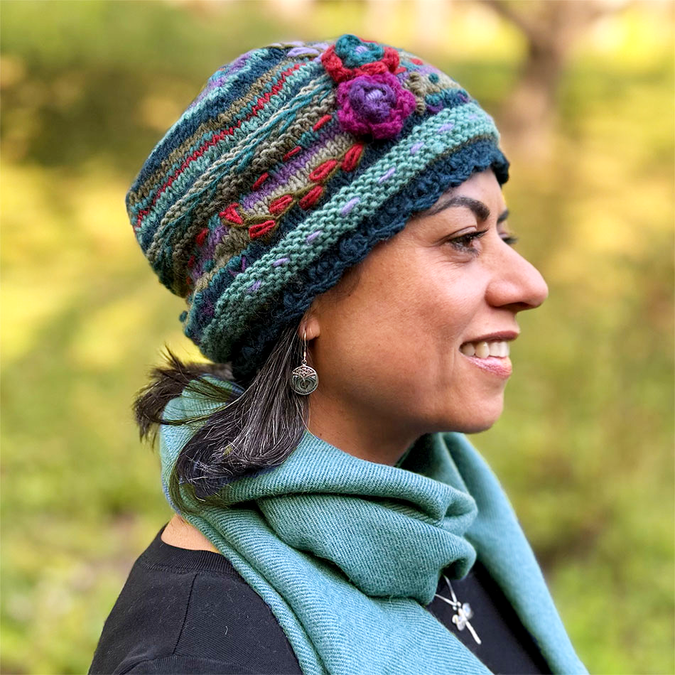 Fair trade handknit wool hat teal and pink and purple flowers.