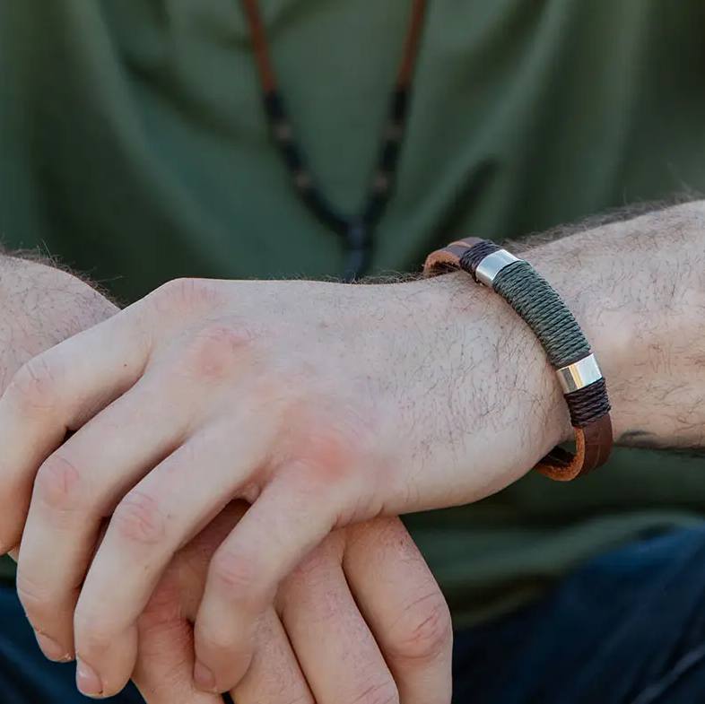 Leather bracelet with metal accents and green wrapping in the middle.  Adjustable slip knot closure.