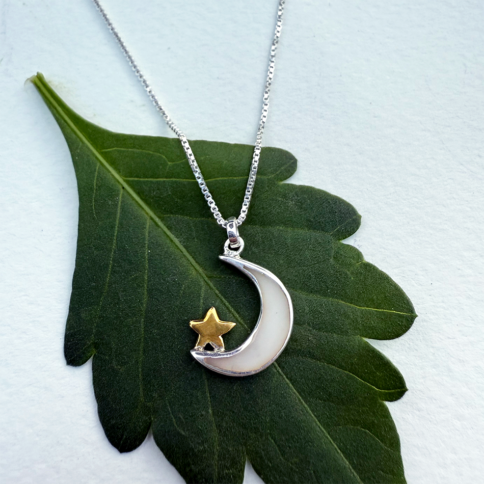 Sterling silver crescent moon and star necklace on silver box chain.