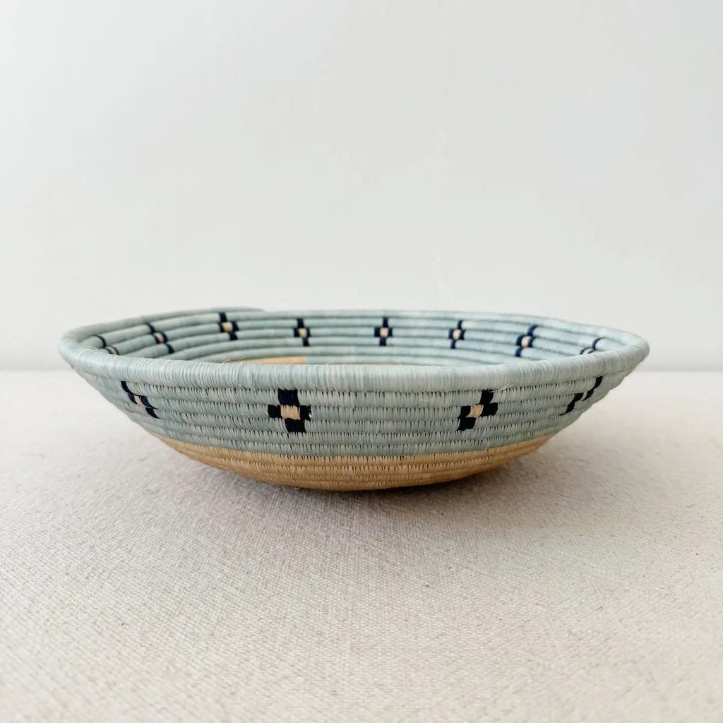 Fair trade basket with sisal and sweetgrass handmade by women artisans in Rwanda, tan center with blue rim and black accent.